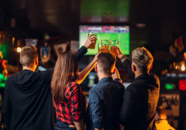 Four football fans toast the TV with pints in a pub