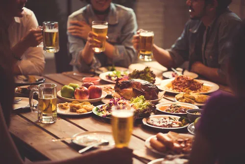 Four friends share a meal and toast each other with beer