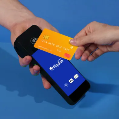 Hand holding a bank card over a Flipdish payment device
