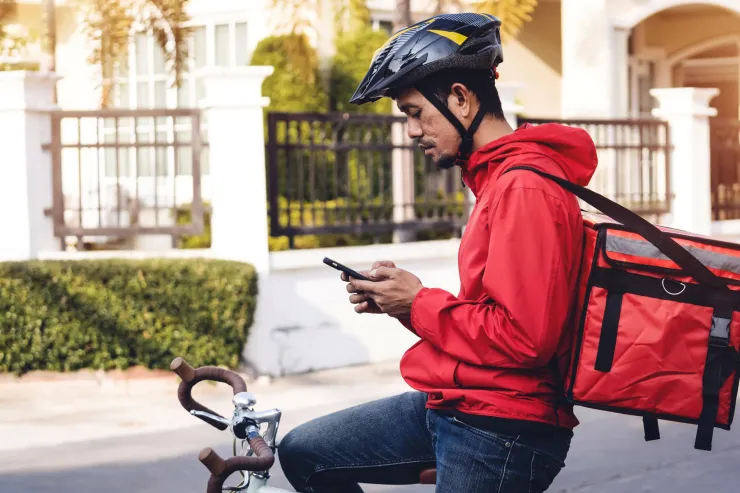 A food delivery cyclist stops to check their phone min