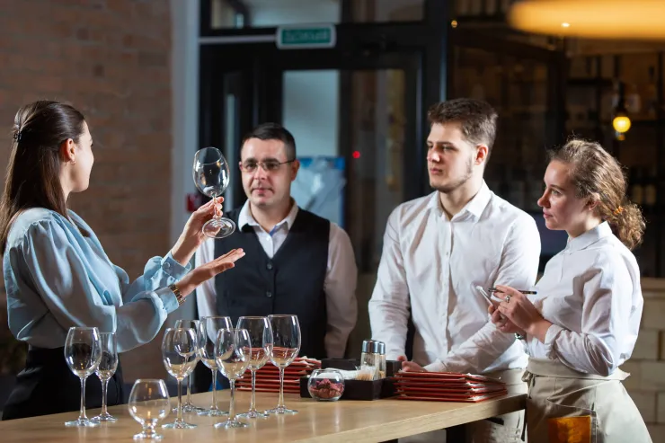Three restaurant staff members taking part in glassware training in a restaurant min