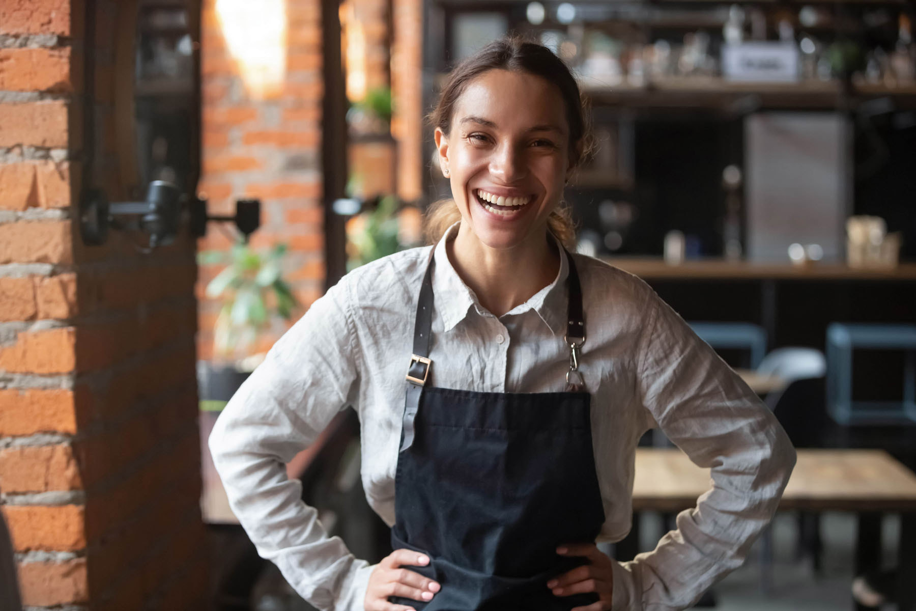 A happy member of wait staff in a linen shirt and apron min