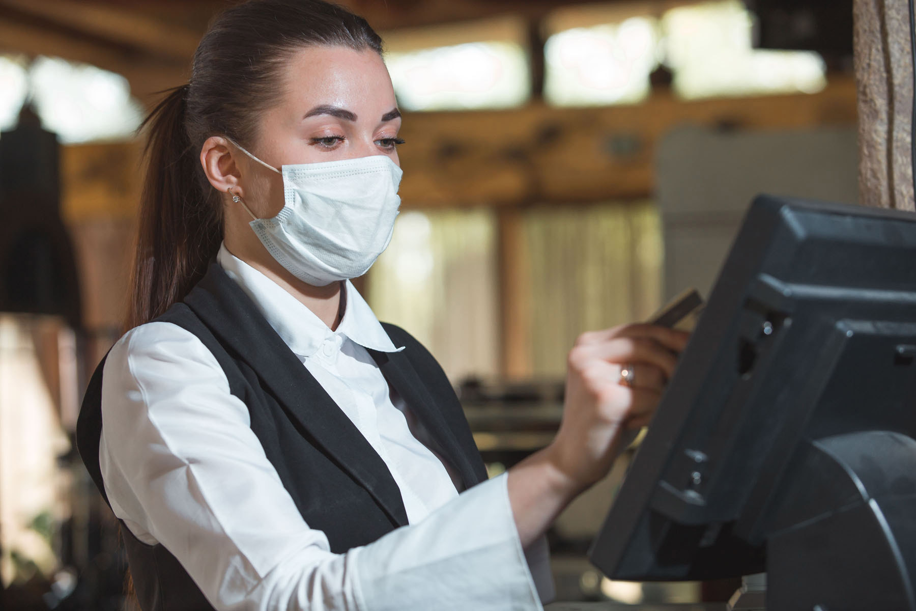 A masked restaurant staff member uses a POS system min