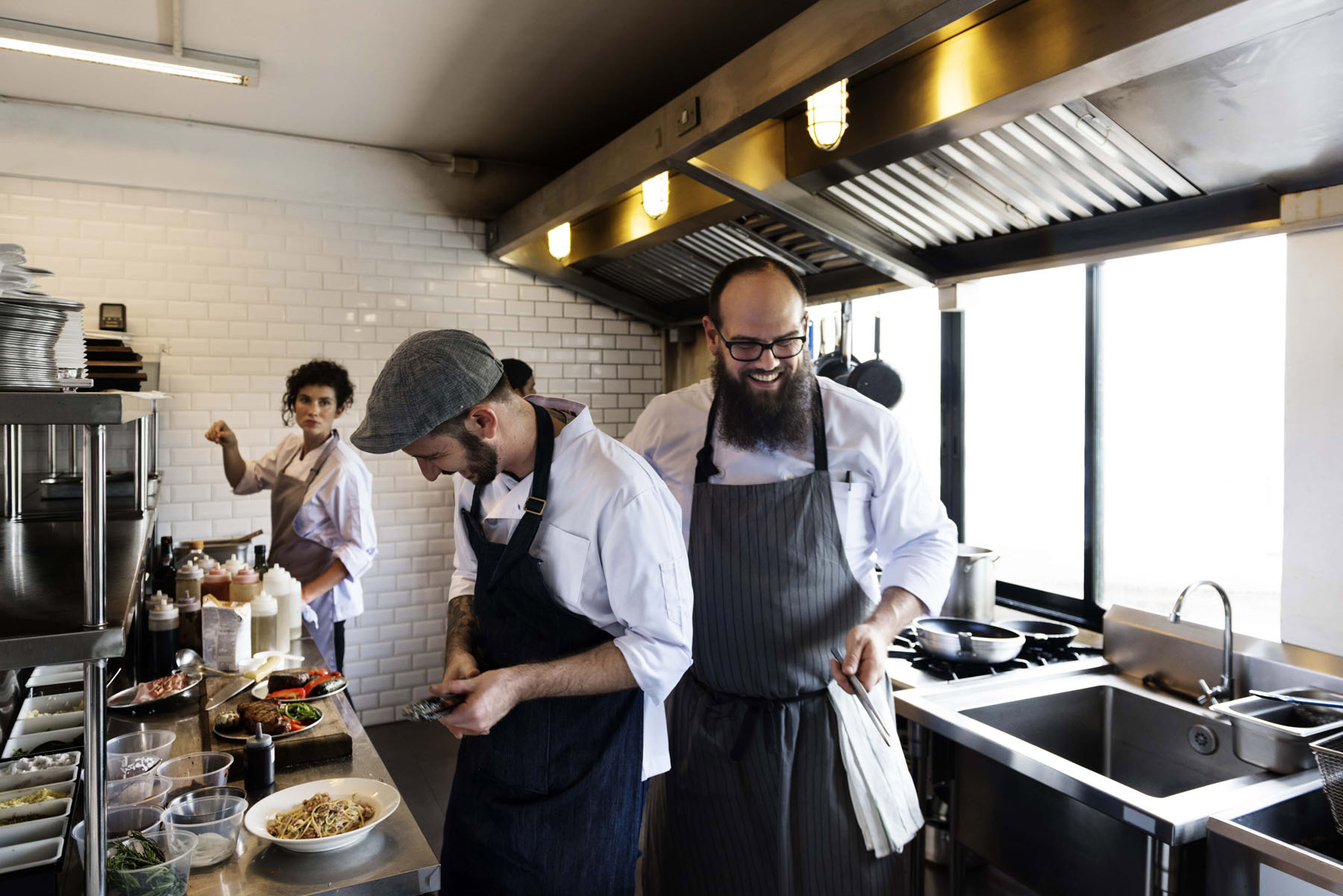 Three chefs joking in a busy kitchen min