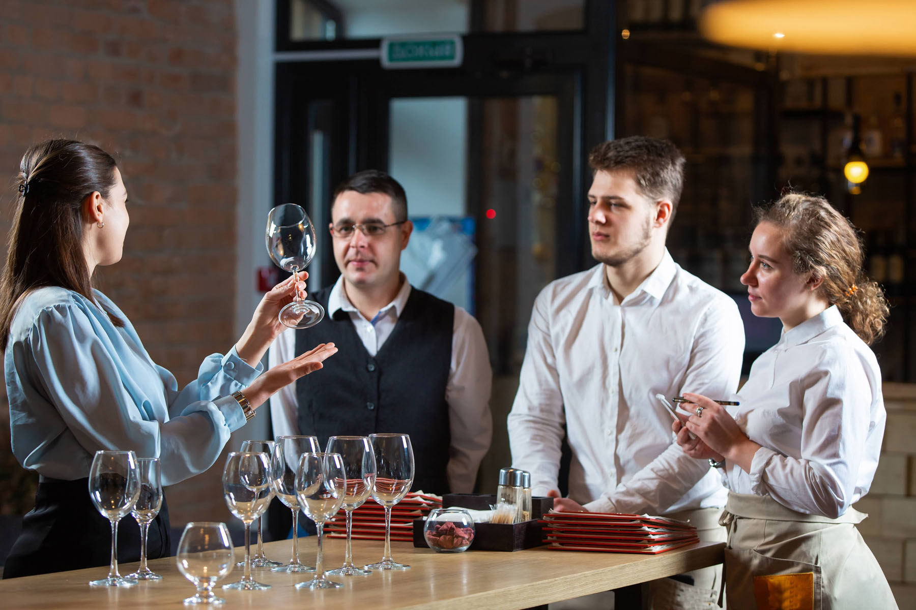 Three restaurant staff members taking part in glassware training in a restaurant min