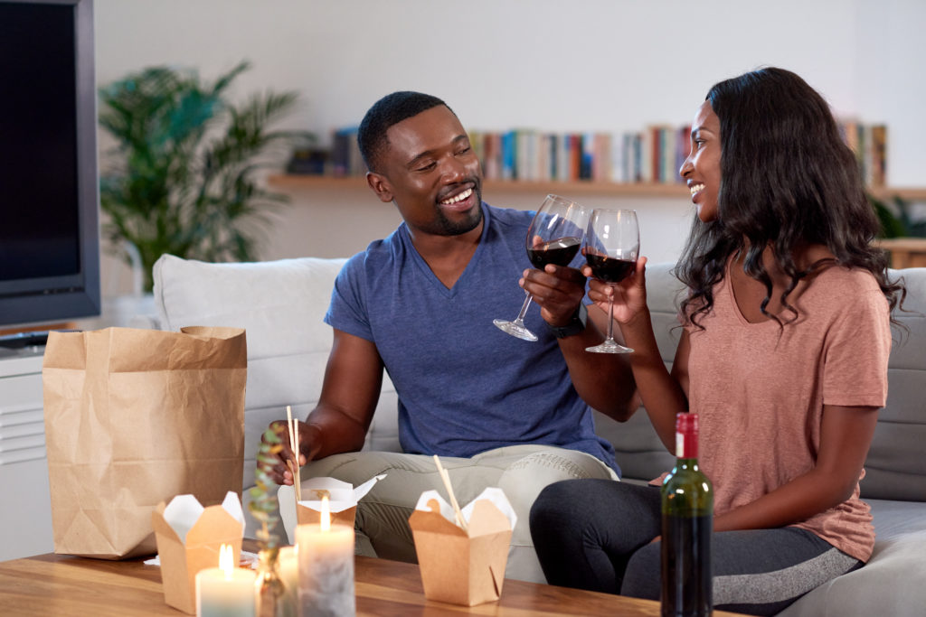 Couple enjoying romantic Valentine's takeaway dinner with glasses of wine