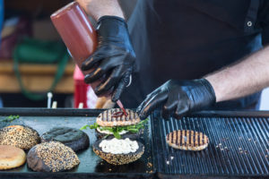 Personnel de cuisine porte des gants lorsqu'il prépare un hamburger